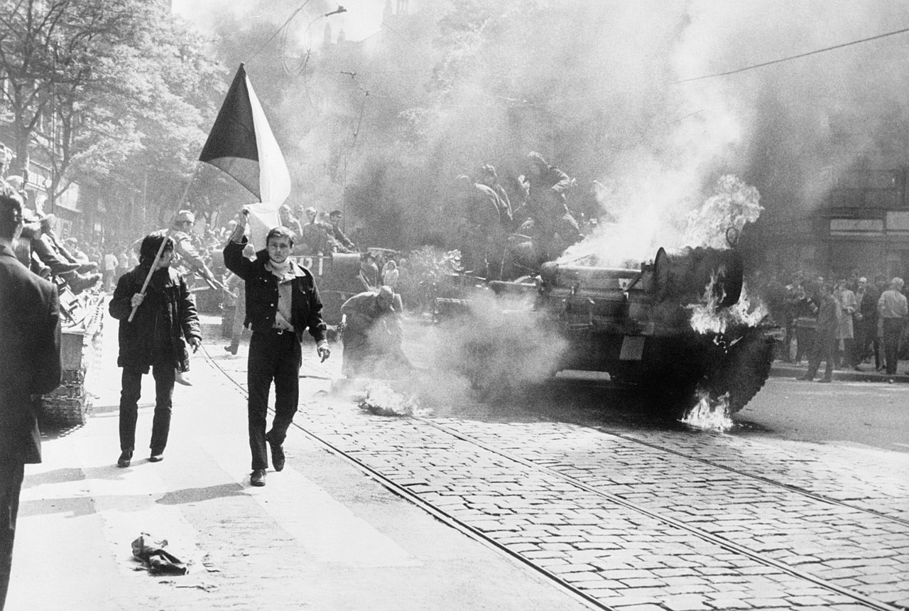 Einwohner von Prag mit Tschechoslowakischer Flagge vor einem brennenden Sowjetischen Panzer. (Central Intelligence Agency CIA)